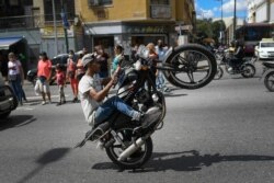 A supporter of President Nicolas Maduro performs a wheelie on his motorbike during a rally during on the same day the opposition organized a people's consultation, in Caracas, Venezuela, Dec. 12, 2020.