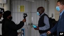 FILE - Passengers have their temperatures taken at the International O.R. Tambo Airport in Johannesburg, Oct. 1, 2020.