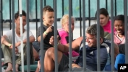 FILE- A young boy plays with recently arrived migrants as they wait in a garage area of the U.S. Customs and Border Protection - Marathon Border Patrol Station, Jan. 4, 2023, in Marathon, Fla.