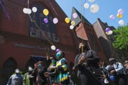 FILE - People who could not attend a service for Bishop Carl Williams Jr. because of COVID curbs on the size of gatherings release balloons in his memory in front of his Brooklyn, N.Y., church, May, 21, 2020.