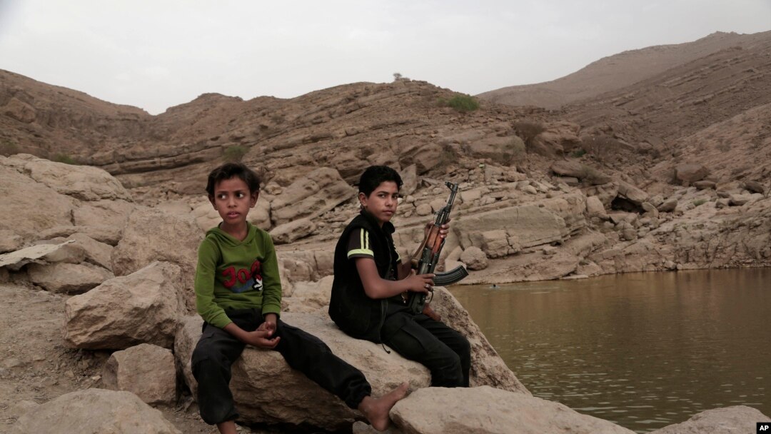 FILE - A 17-year-old boy holds his weapon in High dam in Marib, Yemen, July 30, 2018. Experts say child soldiers are “the firewood” in the inferno of Yemen’s civil war, trained to fight, kill and die on the front lines.