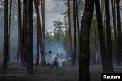 A worker carries a shovel he used to dig a firebreak to contain a forest fire near Yarova, Sviati Hory National Nature Park, Donetsk region, amid Russia's attack on Ukraine, July 29, 2024.