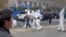In this photo provided Nov 23, 2022, security personnel in protective clothing were seen taking away a person during protest at the factory compound operated by Foxconn Technology Group in Zhengzhou, China.