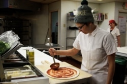 FILE - Andrea Ledesma makes pizza at Classic Slice in Milwaukee, Jan. 9, 2017. The 28-year-old has a four-year degree and quit a higher paying job because it made her miserable. She thought she'd be making more by now and she's not alone.