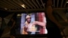 People walk past a screen showing a movie trailer for the Chinese film "Upstream", outside a cinema at a shopping mall in Shanghai, China Aug. 14, 2024.