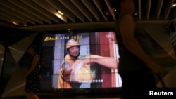 People walk past a screen showing a movie trailer for the Chinese film "Upstream", outside a cinema at a shopping mall in Shanghai, China Aug. 14, 2024.