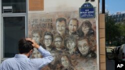 Umuntu ureba igishushanyo cy'ababakoreraga ikinyamakuru Charlie Hebdo baguye mu gitero cy'abiyahuzi bagabye ku cyicaro cy'icyo kinyamakuru.