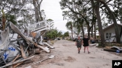 Charlene Huggins, and her daughter-in-law, Katelyn Huggins, right, walk past the destruction on their street in the aftermath of Hurricane Helene, in Horseshoe Beach, Florida, Sept. 28, 2024.