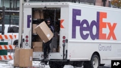 FILE - A FedEx delivery person carries a package from a truck on Nov. 17, 2022, in Denver. 