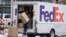 FILE - A FedEx delivery person carries a package from a truck on Nov. 17, 2022, in Denver. 