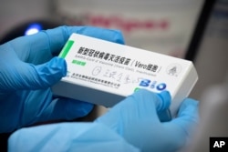 FILE - A medical worker holds a package for a Sinopharm vaccine at a vaccination facility in Beijing, Jan. 15, 2021.