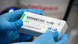 FILE - A medical worker holds a package for a Sinopharm vaccine at a vaccination facility in Beijing, Jan. 15, 2021.