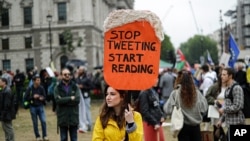 FILE - People hold placards with anti-Trump messages in central London, near the end of a protest against the state visit of President Donald Trump, June 4, 2019. 