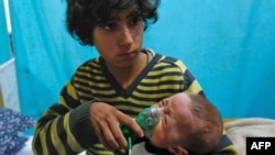 敘利亞首都大馬士革郊區東古塔杜馬鎮遭到毒氣襲擊，一名男孩在一家臨時醫院抱著戴上氧氣面罩的嬰孩(2018年1月22日資料照片)
