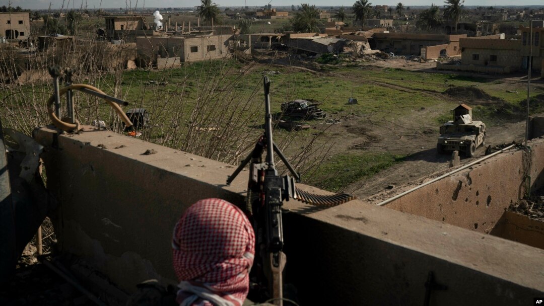 A U.S.-backed Syrian Democratic Forces fighter stands atop a building used as a temporary base near the last land still held by Islamic State militants in Baghouz, Syria, Feb. 18, 2019.