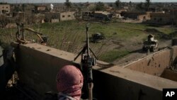 A U.S.-backed Syrian Democratic Forces fighter stands atop a building used as a temporary base near the last land still held by Islamic State militants in Baghouz, Syria, Feb. 18, 2019.