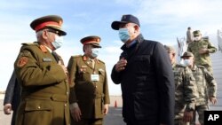 Turkey's Defense Minister Hulusi Akar, center, and other top Turkish military commanders, right, greet Libyan commanders, at airport, in Tripoli, Libya, Dec, 26, 2020.