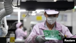 Seorang pekerja tampak mengecek papan sirkuit elektronik pada salah satu bagian produksi di Pabrik Gree, di Wuhan, China, pada 16 Agustus 2021. (Foto: China Daily via Reuters)