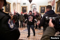 Pendukung Presiden Donald Trump menghadapi polisi ketika pendukung Trump berdemonstrasi di lantai dua US Capitol dekat pintu masuk Senat setelah menerobos pertahanan keamanan, di Washington, AS, 6 Januari 2021. (Foto: Reuters)