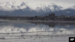 FILE- In this Feb. 12, 2016, photo, the Chugach Mountains and the buildings of downtown Anchorage, Alaska, are reflected in the still waters of Cook Inlet. Oil from an underwater pipeline leak was discovered in the inlet, April 1, 2017.