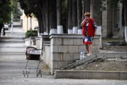 A woman collects drinking water from a spring on a street during the ongoing fighting between Armenia and Azerbaijan, in the breakaway Nagorno-Karabakh's main city of Stepanakert, Oct 2, 2020.