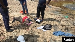 Policías de Curazao observan restos de ropa recuperados en una playa de la isla donde fueron encontrados los restos de cuatro venezolanos que perecieron en un naufragio el martes 9 de enero de 2018. Willemstad, Curazao, enero 11 de 2018.