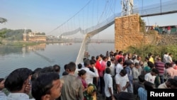 People gather as rescuers search for survivors after a suspension bridge collapsed in Morbi town in the western state of Gujarat, India, Oct. 31, 2022. 