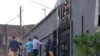 Passers-by walk past policemen standing guard at the entrance of the Livs night-club where a deadly fire occurred in the Bastos district of Yaounde, Jan. 23, 2022.