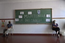 Ancianos esperan tras recibir la vacuna rusa Sputnik V contra la COVID-19, en un centro temporal de vacunación en una escuela pública en Ezeiza, Buenos Aires, Argentina, el 18 de febrero de 2021.
