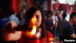 Seorang perempuan menyalakan dupa dalam perayaan Tahun Baru Imlek di Vihara Dharma Bhakti di Jakarta, 28 Januari 2017. (Foto: Reuters)