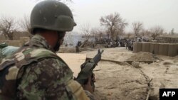 An Afghan soldier is seen in a guard tower at a military base as civilians gather outside in Panjwai. (AP)