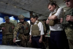 Ukrainian President Volodymyr Zelenskiy, center, listens to a serviceman as he visits the war-hit Donetsk region, eastern Ukraine, Oct. 14, 2019.