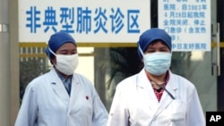 FILE PHOTO - Chinese health workers wear protective garments and masks walk in front of the clinic marked as "atypical pneumonia clinic zone", Beijing, China. 