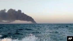 This image made from a video released on Wednesday, June 2, 2021 by Asriran.com, shows smoke rising from Iran's navy support ship Kharg in the Gulf of Oman.