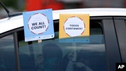 Dos niños sostienen carteles a través del vidrio de un auto en referencia al Censo de 2020 en EE.UU. en un evento en Dallas, Texas. Junio 25 de 2020.