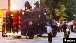 La police observe depuis une voiture blindée les manifestants rassemblés après la mort par balle d'un civil à St. Louis, Missouri, le 19 août 2015. 