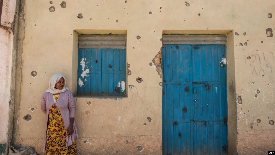 FILE - A woman leans on the wall of a damaged house that was shelled as federal-aligned forces entered the city, in Wukro, north of Mekele, capital of Tigray, March 1, 2021.