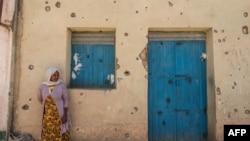 FILE - A woman leans on the wall of a damaged house that was shelled as federal-aligned forces entered the city, in Wukro, north of Mekele, capital of Tigray, March 1, 2021.