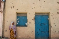 FILE - A woman leans on the wall of a damaged house that was shelled as federal-aligned forces entered the city, in Wukro, north of Mekelle, capital of Tigray. The region has been beset by hostilities since November.