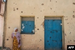 FILE - A woman leans on the wall of a damaged house that was shelled as federal-aligned forces entered the city, in Wukro, north of Mekele, capital of Tigray, March 1, 2021.