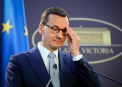 FILE - Polish Prime Minister Mateusz Morawiecki adjusts his glasses during a press statement in Bucharest, Romania, Sept. 18, 2019.
