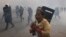 A protester escapes from riot police officers who fire tear gas grenades during a protest in Phnom Penh, Jan. 27, 2014.