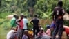 FILE - Children gather around a wooden boat conveying two bodies of a boat accident, in Mukwija in Eastern Congo, Wednesday Jan. 6, 2021. On Friday, October 13, 2023, an overloaded boat carrying 300 people capsized near the town of Mbandaka in Equateur Province.