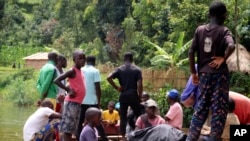 FILE - Children gather around a wooden boat conveying two bodies of a boat accident, in Mukwija in Eastern Congo, Wednesday Jan. 6, 2021. On Friday, October 13, 2023, an overloaded boat carrying 300 people capsized near the town of Mbandaka in Equateur Province.