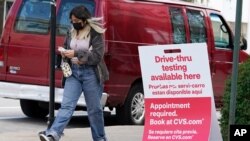 A woman wears a face mask as she walks past an information sign of COVID-19 testing in Chicago, Ill., Aug. 13, 2021.