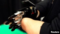 FILE - Mincheng Ni, who lost both his hands in an accident, demonstrates a Brain Robotics artificial intelligence powered prosthetic hand at CES in Las Vegas, Nevada, U.S., Jan. 7, 2018.