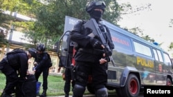 Indonesian anti-terrorism policeman holds a rifle as others seize crude bombs at Riau University building in Pekanbaru, Sumatra Island, Indonesia, June 2, 2018. 