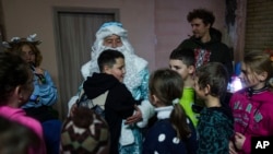 A boy hugs a man wearing a St. Nicholas costume during celebrations of St. Nicholas Day in Izium, Ukraine, Dec. 6, 2024. 