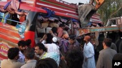 Petugas penyelamat Pakistan dan sukarelawan mengeluarkan penumpang dari bis yang rusak di lokasi kecelakaan di Pannu Aqil, Pakistan, Minggu, 20 April 2014.