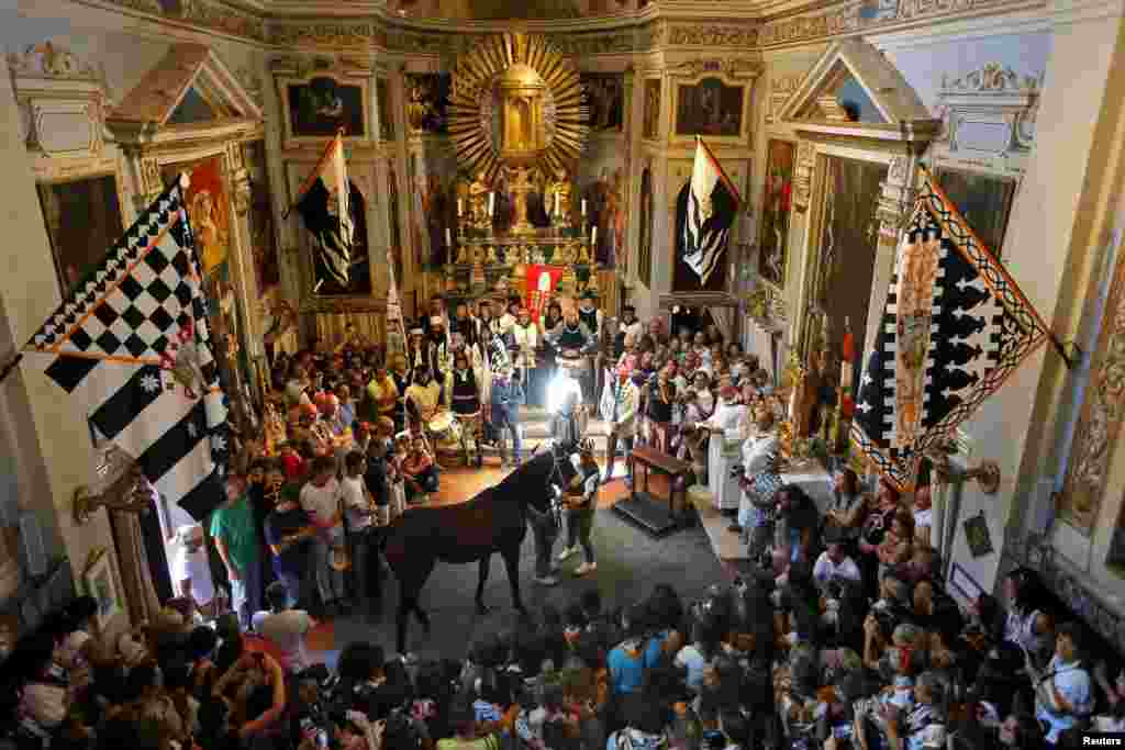 Supporters look at jockey Jonathan Bartoletti (C) and his horse, Bened of the Lupa (Wolf) during a blessing ceremony in a church, before the Palio race in Siena, Italy.